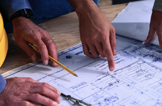 Architects and project managers examining building plans at a construction site