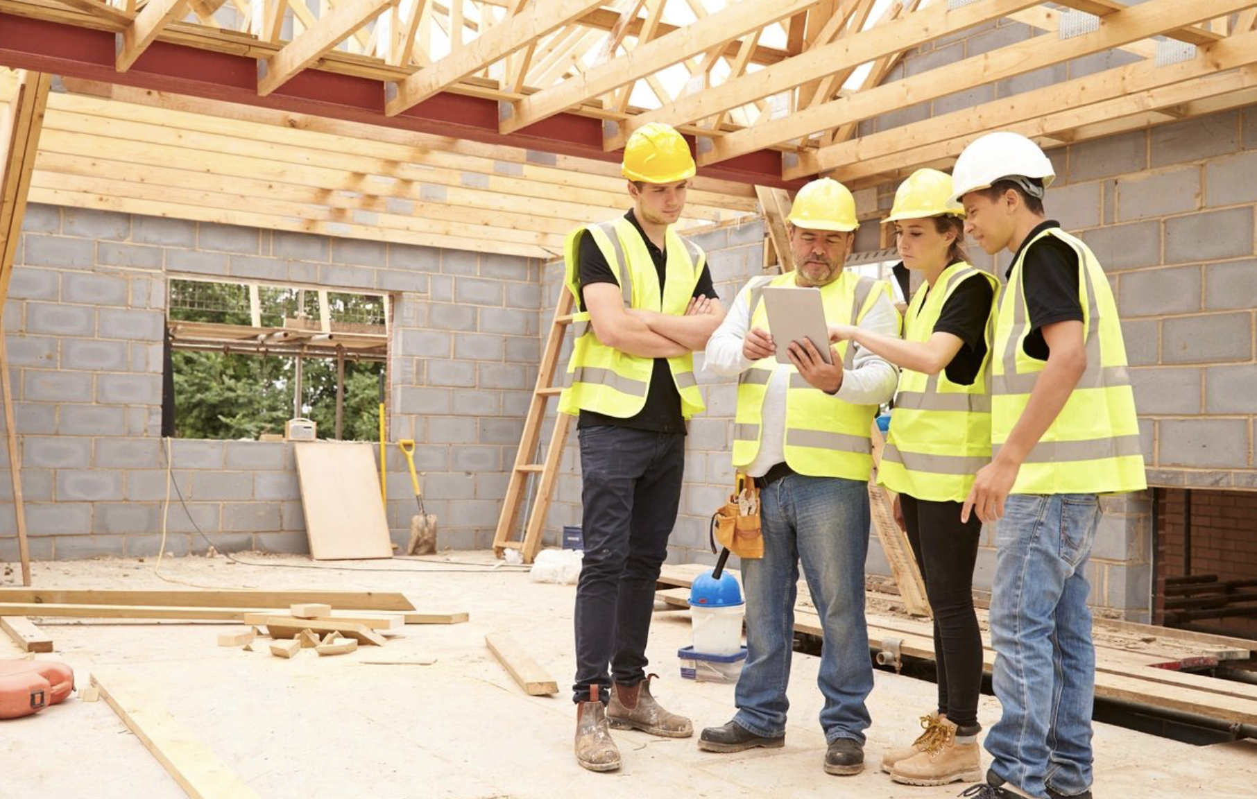 Project managers reviewing construction blueprints on site with digital tablets